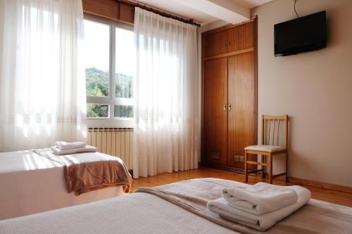 OrtigueroLa Terraza de Picos的一间卧室设有两张床、一台电视和一扇窗户。