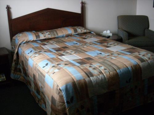 隆格伊圣休伯特大汽车旅馆的一间卧室,卧室内配有一张床和一把椅子