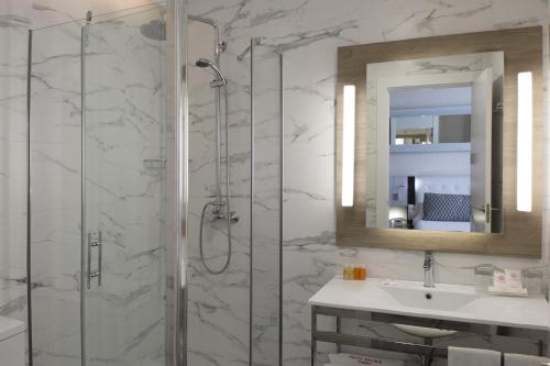 马德里Petit Palace Arenal的带淋浴、盥洗盆和镜子的浴室