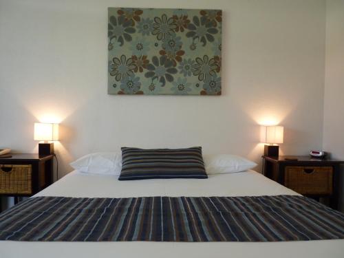 佩诺拉库纳瓦拉汽车旅馆旅舍的一间卧室配有一张带两盏灯的床,墙上挂有一幅画