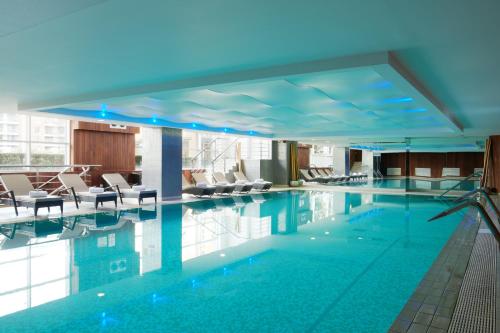 伦敦The Chelsea Harbour Hotel and Spa的一座配有桌椅的酒店游泳池