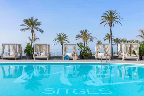 锡切斯特乐玛ME锡切斯酒店的一个带躺椅和棕榈树的游泳池