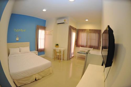 曼谷花园生活旅馆的一间卧室配有一张床、一张书桌和一台电视