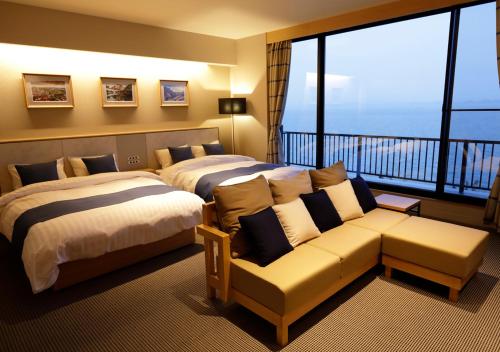 松江市玉造国际日式旅馆的酒店客房设有两张床、一张沙发和一个阳台。