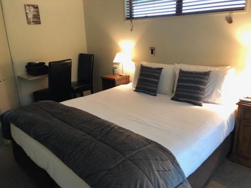 莫阿纳Lake Brunner Longhouse的卧室配有一张带黑色枕头的大型白色床。