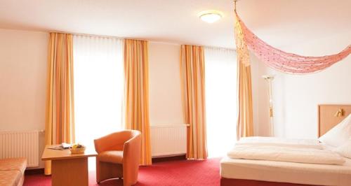 图特林根泽尔滕巴彻霍夫酒店的配有一张床和一把椅子的酒店客房