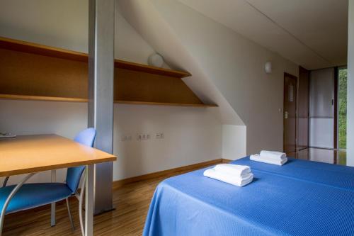 维戈Residencia Universitaria O Castro的一间设有蓝色床和桌椅的房间