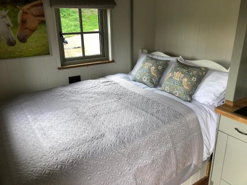 BransgoreLuxury Shepherds Hut的卧室配有带枕头的白色床和窗户。