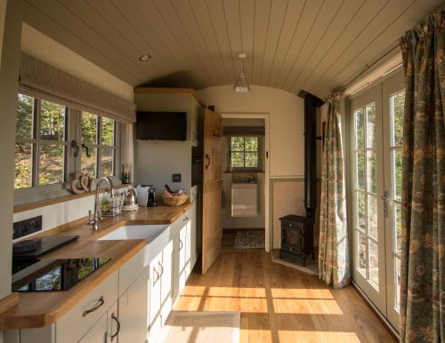 BransgoreLuxury Shepherds Hut的厨房配有白色橱柜、木地板和窗户。