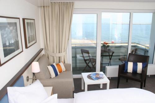 黑尔戈兰岛米拉玛度假屋的带沙发的客厅和带阳台的客房。