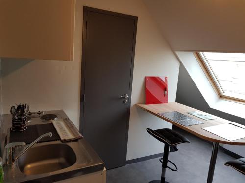 维尔Appartement Hyper centre - Quartier du château de Vire的带水槽的厨房和带窗户的书桌