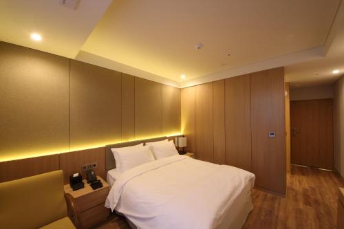 华城市高丽良宵H酒店的卧室配有一张白色大床和橱柜。