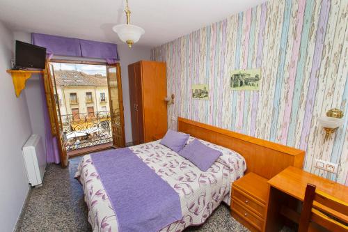 罗德里戈城Hostal Plaza的一间卧室配有一张床、一张书桌和一个窗户。