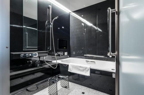 京都京都雅然居酒店的黑白浴室设有浴缸和水槽