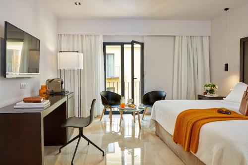 塞维利亚雷伊阿方索X酒店的酒店客房,配有一张床、一张桌子和椅子