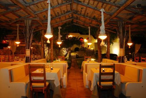 蓬扎圣多米蒂娜大酒店的餐厅配有白色的桌椅和灯光