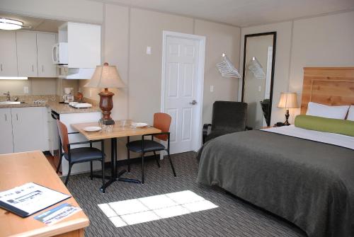 道森市Triple J Hotel的酒店客房设有一张床铺、一张桌子和一间厨房。