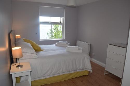 伦敦德里Derry-Londonderry city centre waterfront appartment的一间卧室配有一张带白色床单的床和一扇窗户。