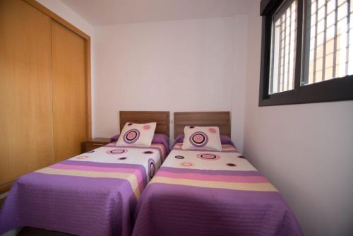 阿瓜杜尔塞apartamento aguadulce playa con WIFI的紫色床单的客房内的两张床