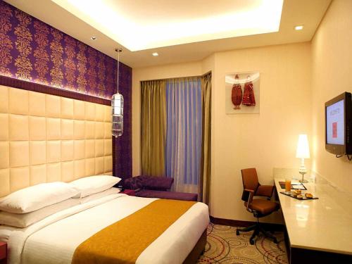 新德里新德里大都市温泉酒店的配有一张床和一张书桌的酒店客房