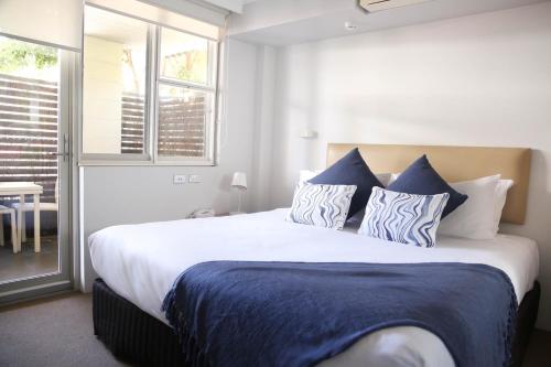 悉尼布伦海姆酒店的一间卧室配有一张带蓝白色枕头的大床