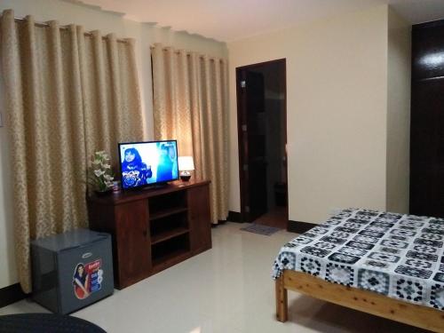 马尼拉卢尔德宾馆的一间设有床铺的房间和一个带电视机的橱柜