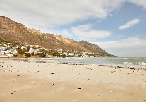 戈登湾First Group Cape Gordonia的一座以城镇和山脉为背景的海滩