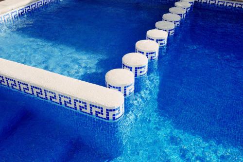 普拉亚登博萨Los Escondidos Ibiza的游泳池里的一排白凳子