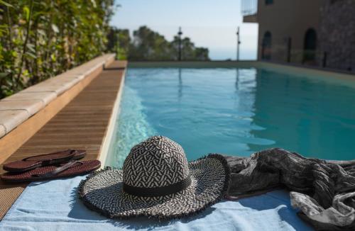 陶尔米纳都卡雷别墅酒店的游泳池旁的帽子和拖鞋