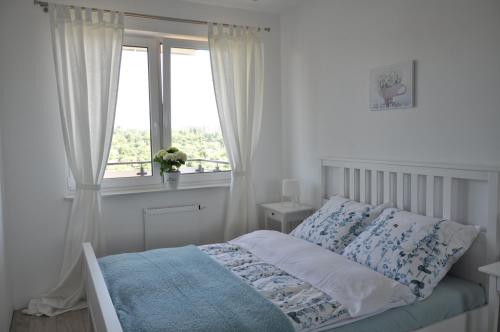 奥尔什丁Apartament Zielone Tarasy的白色的卧室设有床和窗户