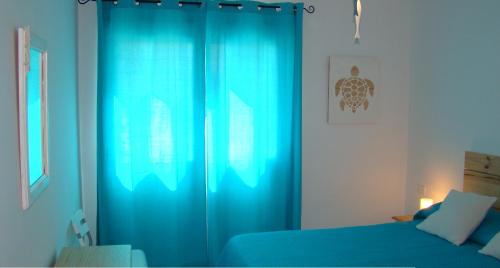 厄尔梅达诺The Beach House的一间卧室配有蓝色窗帘和一张床