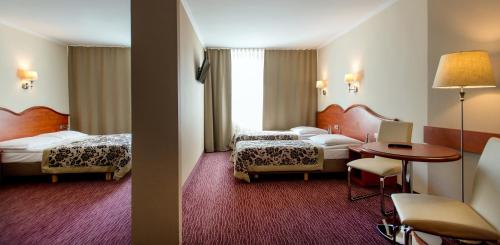 克拉科夫克拉库斯酒店的酒店客房设有两张床和一张桌子。