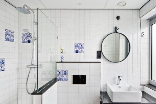 阿姆斯特丹城市洛奇酒店的白色瓷砖浴室设有水槽和镜子