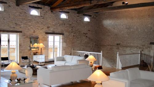 盖亚克Domaine de Perches的客厅配有白色家具和砖墙