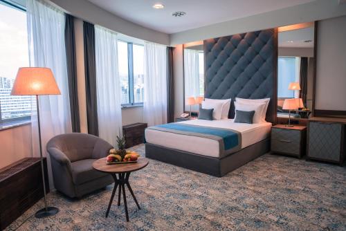 萨拉热窝拉顿广场酒店的配有一张床和一把椅子的酒店客房