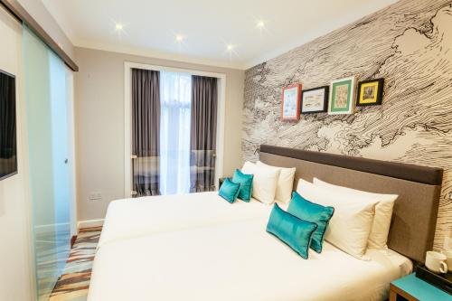 伦敦奥利弗广场酒店的卧室配有带蓝色枕头的大型白色床