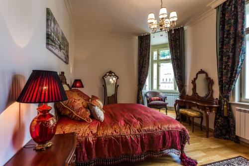 卡罗维发利Karlsbad Prestige的一间卧室配有红色的床和一张带台灯的桌子