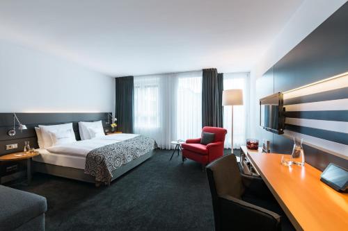 汉堡汉堡麦迪逊酒店的酒店客房,配有一张床和一张红色椅子