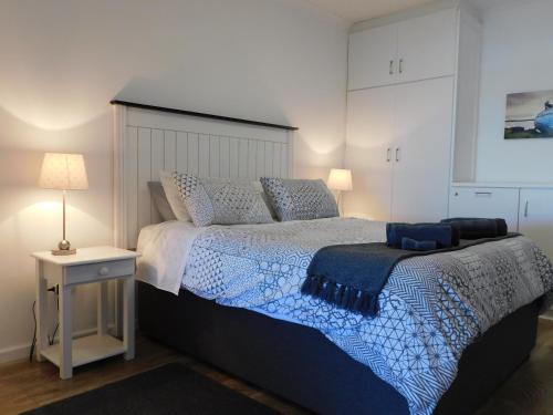 韦尔德里夫Rivertides Self Catering Guest House的一间卧室配有一张带蓝色和白色棉被的床