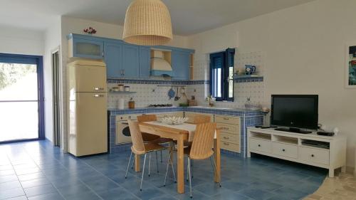 马蒂纳塔Casa Vacanze MARESOLE的厨房配有蓝色橱柜、桌子和电视。