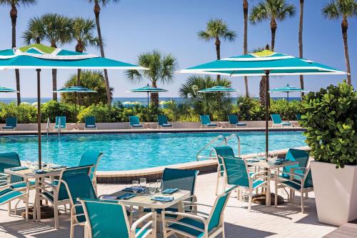 萨拉索塔Resort at Longboat Key Club的游泳池旁的餐厅,配有桌子和遮阳伞