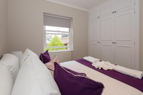 伦敦One bedroom High street kensington Apartment的一间卧室配有两张带紫色和白色枕头的床