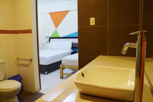 利马Hotel Colors Canada的一间带水槽的浴室和一间带两张床的房间