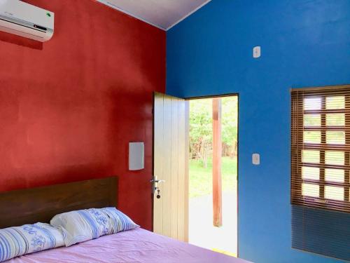 马卡帕Chalé Quintal Amazon的卧室拥有红色和蓝色的墙壁,配有一张床