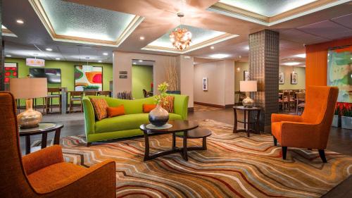 奥兰多贝斯特韦斯特普拉斯环球旅馆的大堂设有绿色沙发和橙色椅子