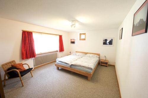 施普吕根Ferienhaus Wanner的一间卧室设有一张床、一个窗口和一把椅子