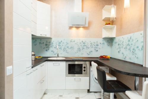阿德勒Апартаменты на Тюльпанов 3的厨房配有白色橱柜和黑色台面
