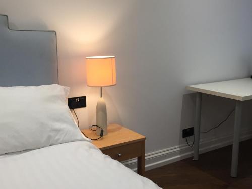伦敦Lexham Gardens Lodge 5的一间卧室配有一张床和一张桌子上的台灯
