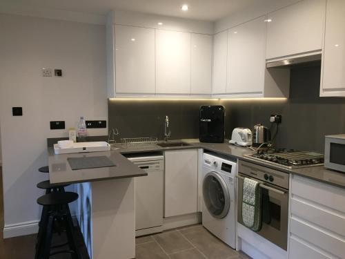 伦敦Lexham Gardens Lodge 5的厨房配有白色橱柜和洗衣机。
