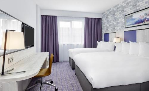 史云顿Leonardo Hotel Swindon的酒店客房配有两张床和一张书桌